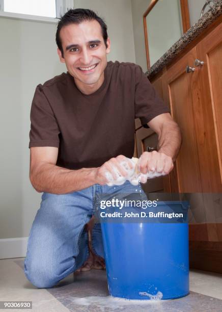 hispanic man cleaning bathroom floor - daily bucket photos et images de collection