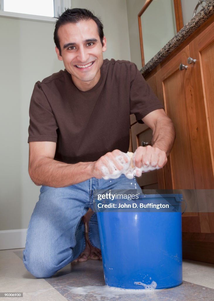 Hispanic man cleaning bathroom floor