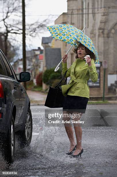 mixed race woman getting splashed by car - puddle stock-fotos und bilder