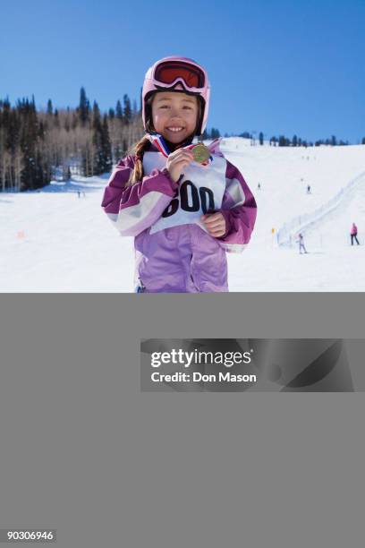 mixed race girl showing off skiing medal - mixed race stock-fotos und bilder