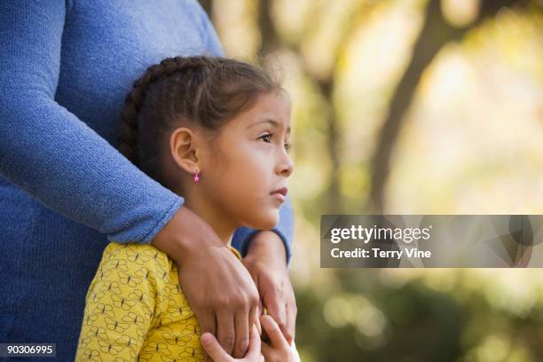 hispanic woman hugging daughter - shy foto e immagini stock