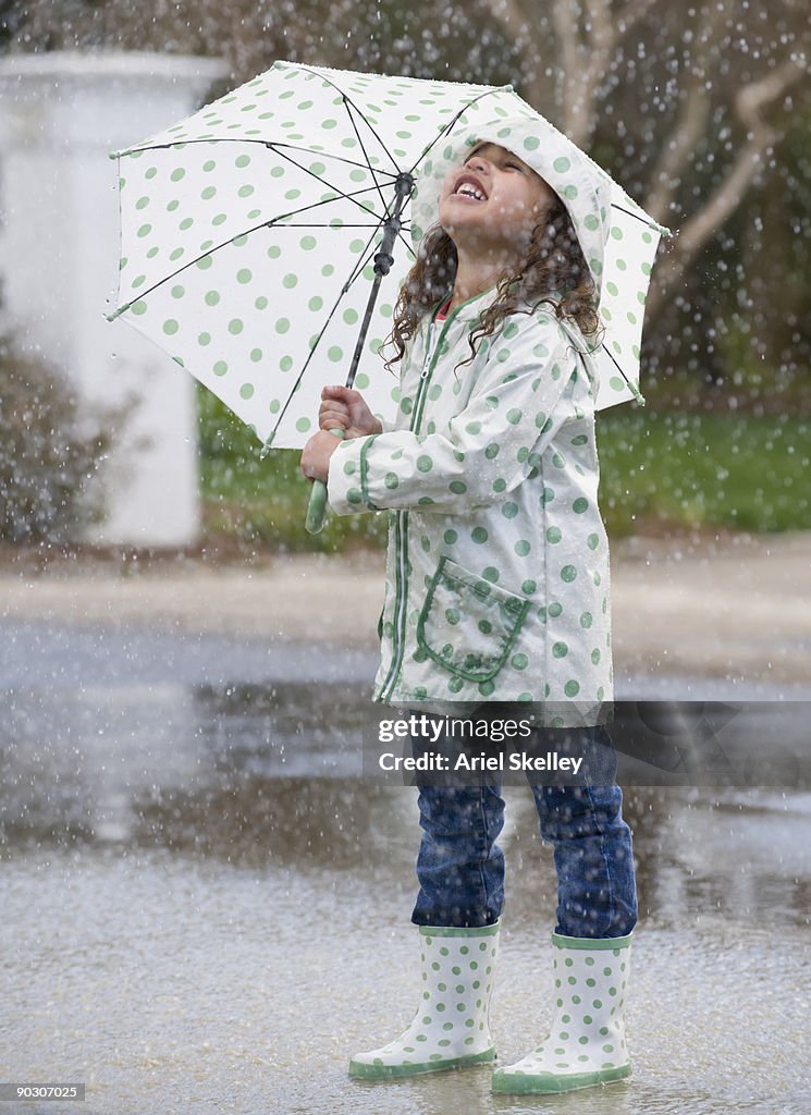 Mixed race girl with umbrella in rain