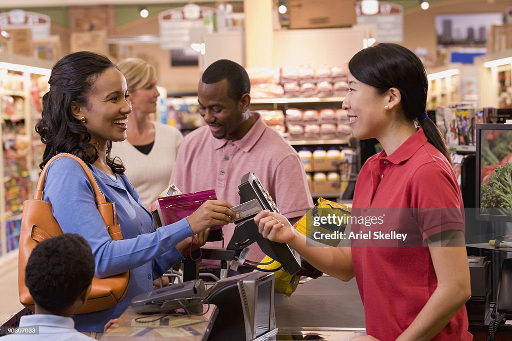 Mixed race woman paying with credit card in grocery store