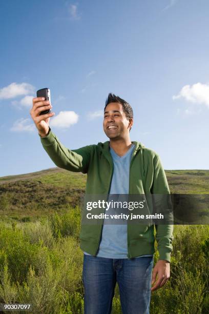 mixed race man taking photo with cell phone - remote location cell phone stock pictures, royalty-free photos & images