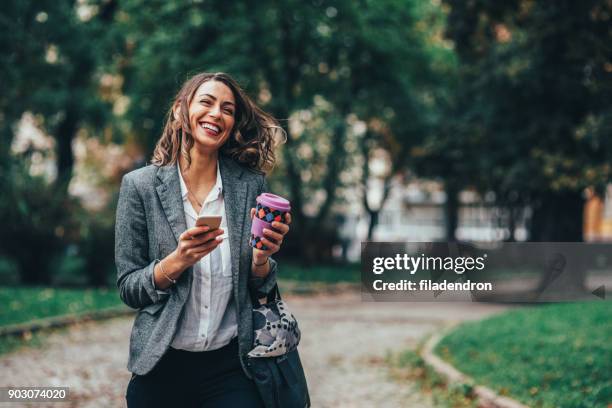 frau sms und kaffeetrinken im park - woman smiling park summer stock-fotos und bilder