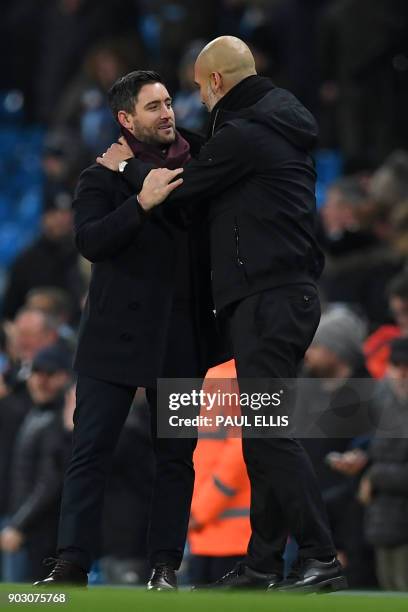 Manchester City's Spanish manager Pep Guardiola consoles Bristol City's English manager Lee Johnson after the English League Cup semi-final first leg...