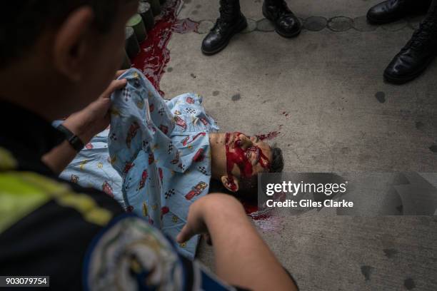 Dr. Chiu holds up a sheet over a victim of gang violence in the busy suburb of Zone 18 on October 21, 2017 in Guatemala City, Guatemala. Guatemala...