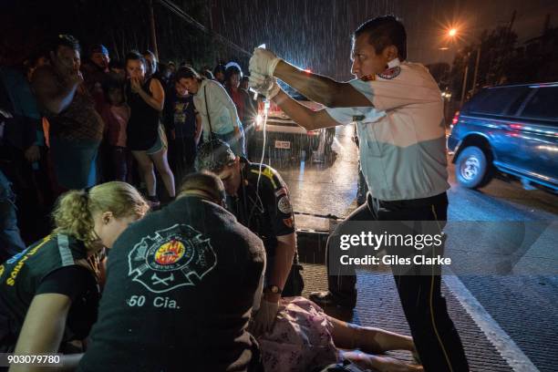 Volunteer paramedic holds an IV over Dr. Chiu for a badly injured woman, who was a victim of a hit and run driver. She died shortly after on the...