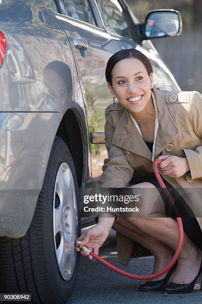 hispanic woman inflating a tire of a car - inflating - fotografias e filmes do acervo