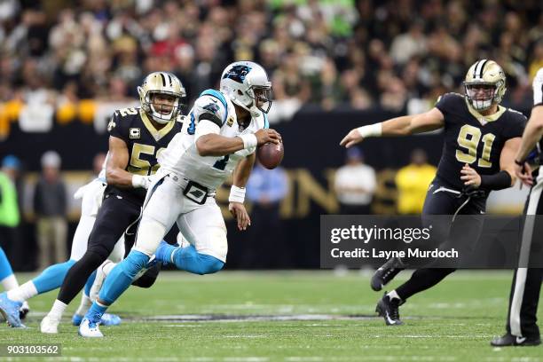 Cam Newton of the Carolina Panthers is chased by Craig Robertson and Trey Hendrickson of the New Orleans Saints during the first half of the NFC Wild...