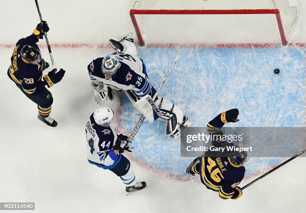 Brendan Guhle and Zemgus Girgensons of the Buffalo Sabres celebrate a first period goal by Jack Eichel against Steve Mason of the Winnipeg Jets...