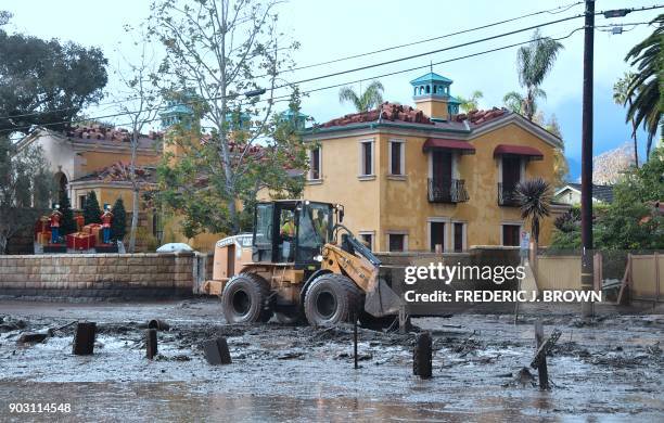 Mud is cleared off a side road off the US 101 freeway near the San Ysidro exit in Montecito, California on January 9, 2018. Mudslides unleashed by a...