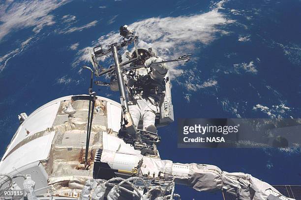 Astronaut James H. Newman, mission specialist, is pictured on the end of Endeavour's remote manipulator system arm during extravehicular activity on...