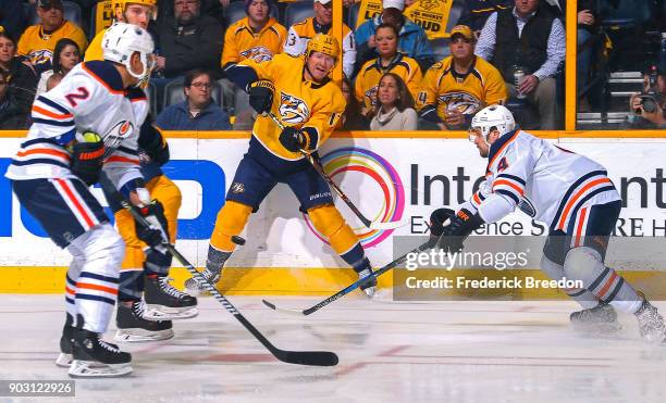 Scott Hartnell of the Nashville Predators passes the puck between Andrej Sekera and Kris Russell of the Edmonton Oilers during the first period at...