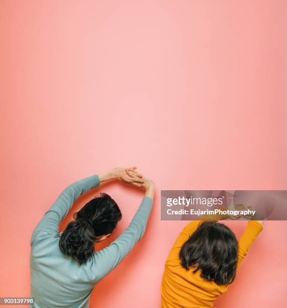 mother and daughter doing stretching together - saturated color stock-fotos und bilder