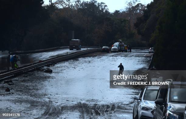 Man wades in a flooded section of the US 101 freeway near the San Ysidro exit in Montecito, California on January 9, 2018. Mudslides unleashed by a...