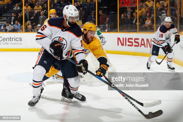 Yannick Weber of the Nashville Predators battles for the puck against Jujhar Khaira of the Edmonton Oilers during an NHL game at Bridgestone Arena on...