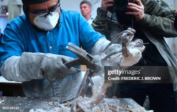 Worker uses a hammer to break the mould of the statue known as 'the Actor' at the American Fine Arts Foundry on January 9, 2018 in Burbank,...