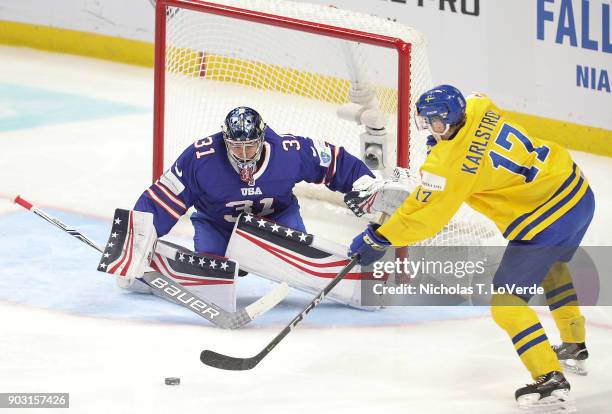 Fredrik Karlström of Sweden passes the puck in front of Joseph Woll of United States during the third period of play in the IIHF World Junior...