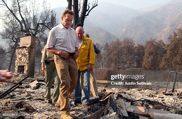 California Gov. Arnold Schwarzenegger and Acting Secretary of Cal E.M.A. Matt Bettenhausen walk through rubble as they tour homes that were burned by...