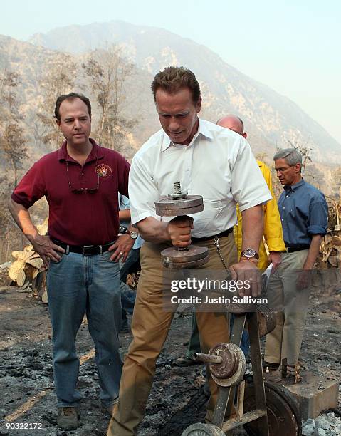 California Gov. Arnold Schwarzenegger lifts a charred dumbbell as U.S. Rep. Adam Schiff and California State Insurance Commissioner Steve Poizner...