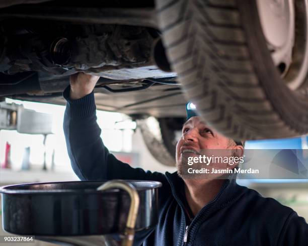 car mechanic working under a vehicle at workshop - notbremse stock-fotos und bilder