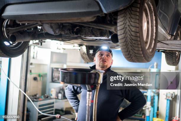 car mechanic working under a vehicle at workshop - notbremse stock-fotos und bilder