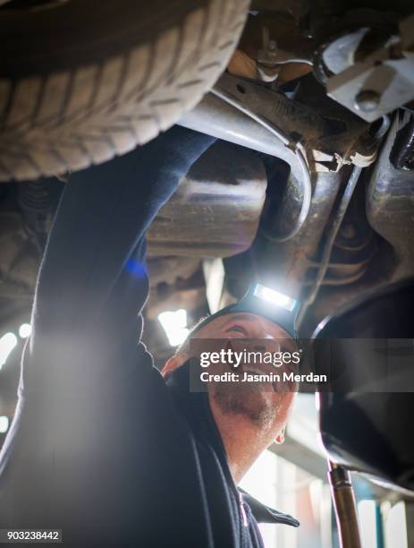 car mechanic working under a vehicle at workshop - notbremse stock-fotos und bilder