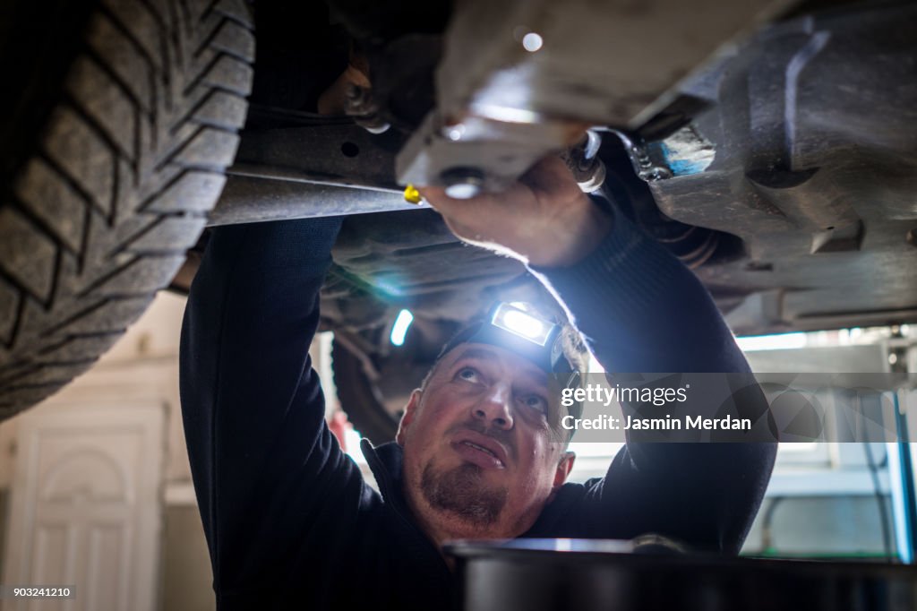 Car mechanic working under a vehicle at workshop