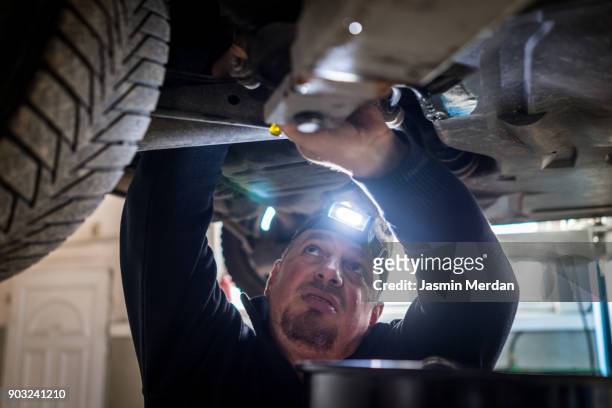 Car mechanic working under a vehicle at workshop