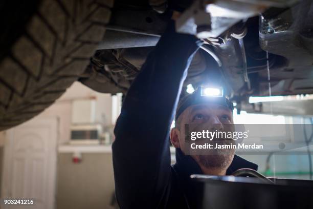 car mechanic working under a vehicle at workshop - notbremse stock-fotos und bilder