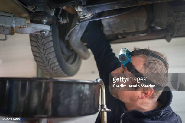 car mechanic working under a vehicle at workshop - notbremse stock-fotos und bilder