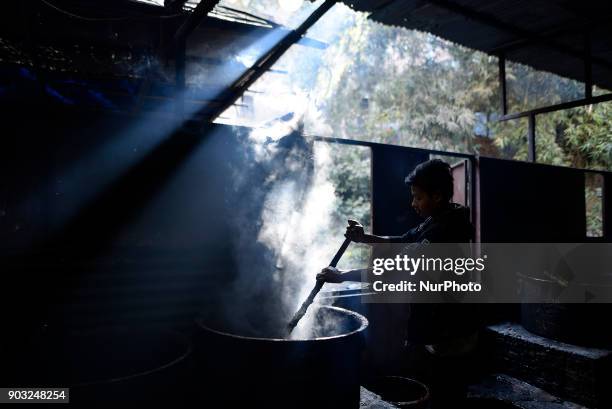 Worker whipping molten Raw Hardened molasses to prepare molasses Chaku at Tokha, Kathmandu, Nepal on Wednesday, January 10, 2018. Molasses Chaku is...