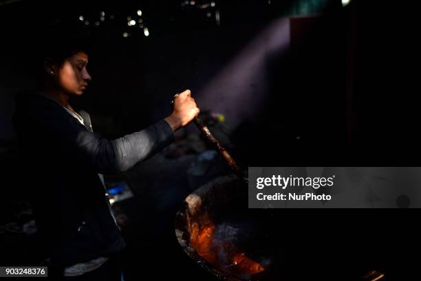 Worker whipping molten Raw Hardened molasses to prepare molasses Chaku at Tokha, Kathmandu, Nepal on Wednesday, January 10, 2018. Molasses Chaku is...