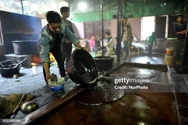 Worker pour semi Hard molasses to cooldown to prepare molasses Chaku at Tokha, Kathmandu, Nepal on Wednesday, January 10, 2018. Molasses Chaku is...