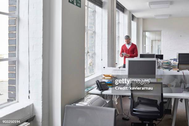 mid adult businessman using digital tablet on an empty office - empty office one person stock pictures, royalty-free photos & images