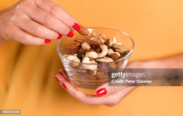 girl eating nuts from a bowl - snack photos et images de collection