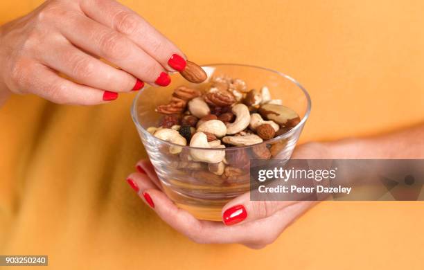 girl eating nuts from a bowl - lanche imagens e fotografias de stock