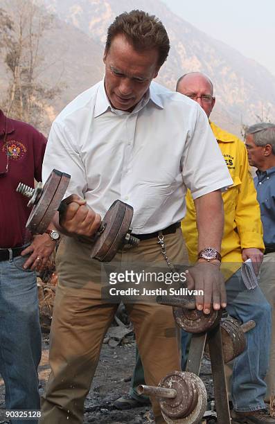 California Gov. Arnold Schwarzenegger lifts a charred dumbbell as he tours homes that were burned by the Station Fire September 2, 2009 at Vogel...