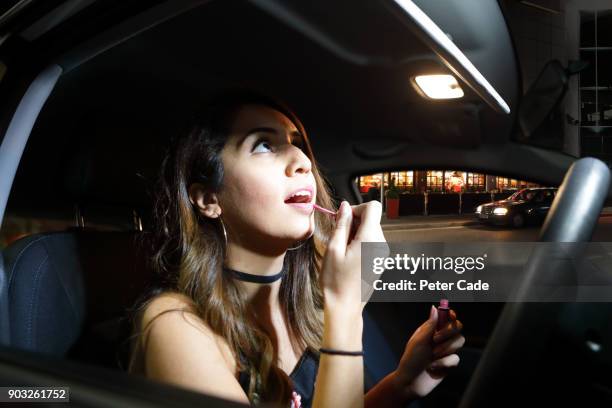 young woman applying lipstick in car on night out - make up looks stock pictures, royalty-free photos & images