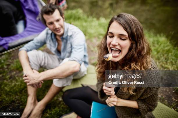 woman with boyfriend eating roasted marshmallow at a tent - in touch with nature stock pictures, royalty-free photos & images