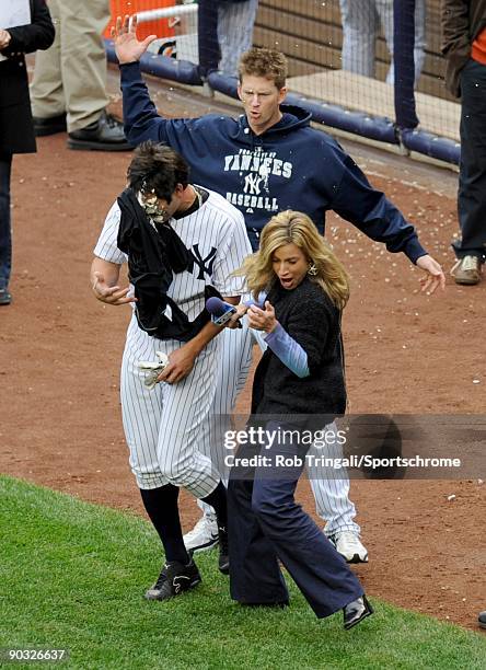 Johnny Damon of the New York Yankees gets a pie in the face by A.J. Burnett while being interviewed by Kim Jones after winning the game with a...