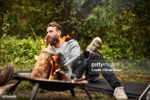 man sitting on mat at camp fire - only mid adult men stock pictures, royalty-free photos & images