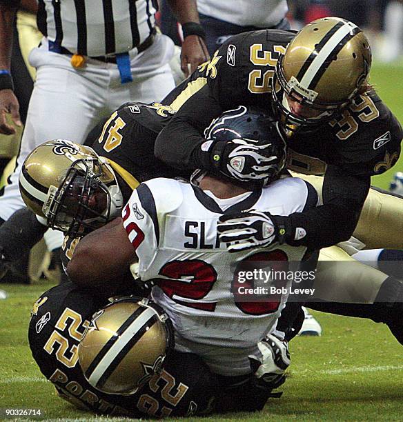 Running back Steve Slaton of the Houston Texans is tackled by Chris Reis, Tracy Porter and Roman Harper of the New Orleans Saints on August 22, 2009...