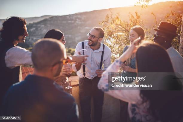 young elegant multi-ethnic friends drinking wine at countryside cottage party - french garden imagens e fotografias de stock