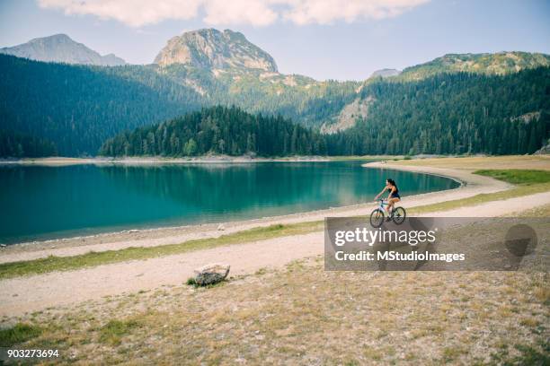 frau mit dem fahrrad am see. - montenegro stock-fotos und bilder