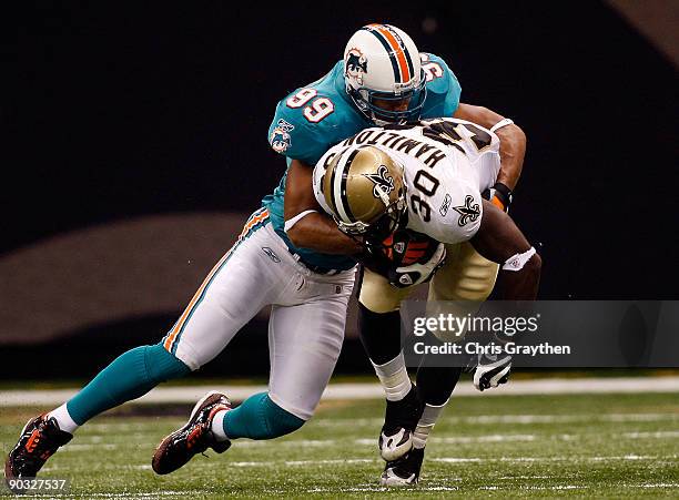 Jason Taylor of the Miami Dolphins tackles Lynell Hamilton of the New Orleans Saints at the Louisiana Superdome on September 3, 2009 in New Orleans,...