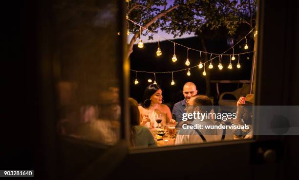 young multi-ethnic friends having rustic dinner party in countryside - large dinner party stock pictures, royalty-free photos & images