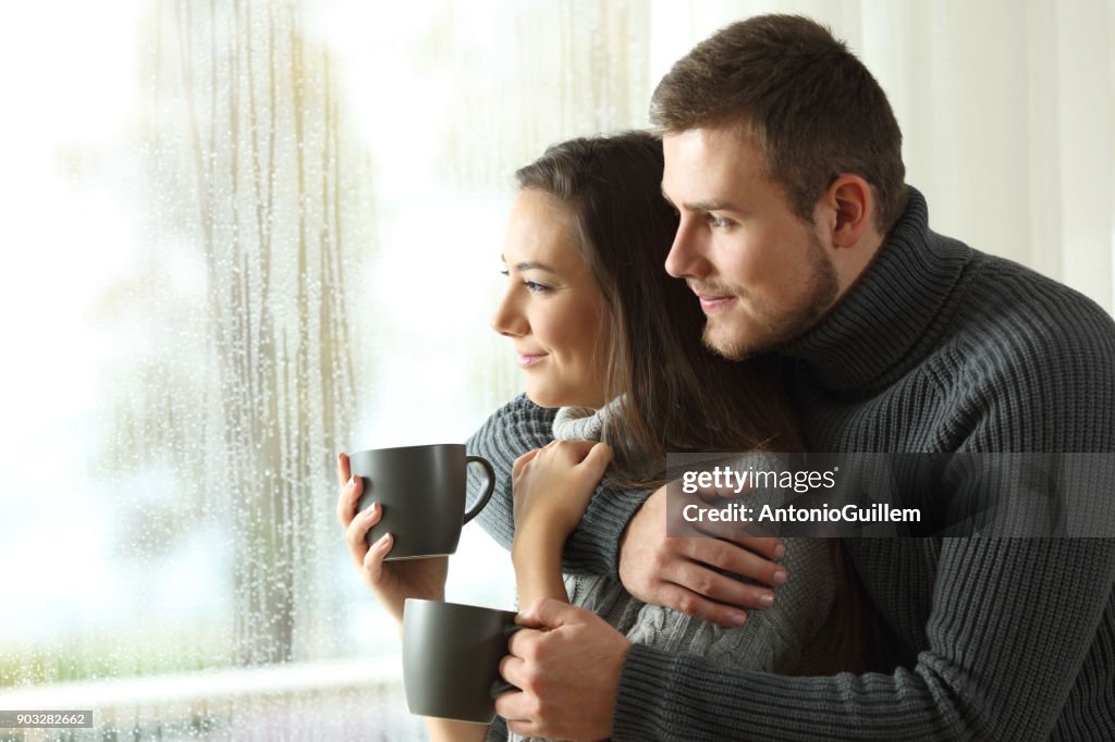 Pareja a través de una ventana en un día lluvioso