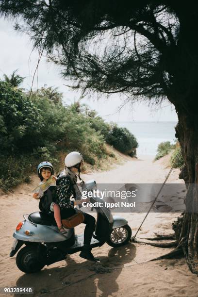 mother and child riding a scooter to beach - mare moto foto e immagini stock